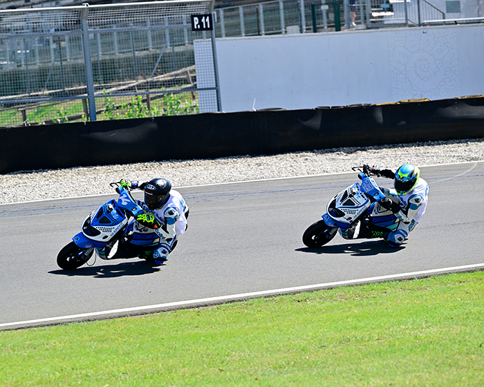 Gara Polini Italian Cup: due piloti su scooter Piaggio Zip Polini in piena piega in curva su asfalto, con erba verde a bordo pista.